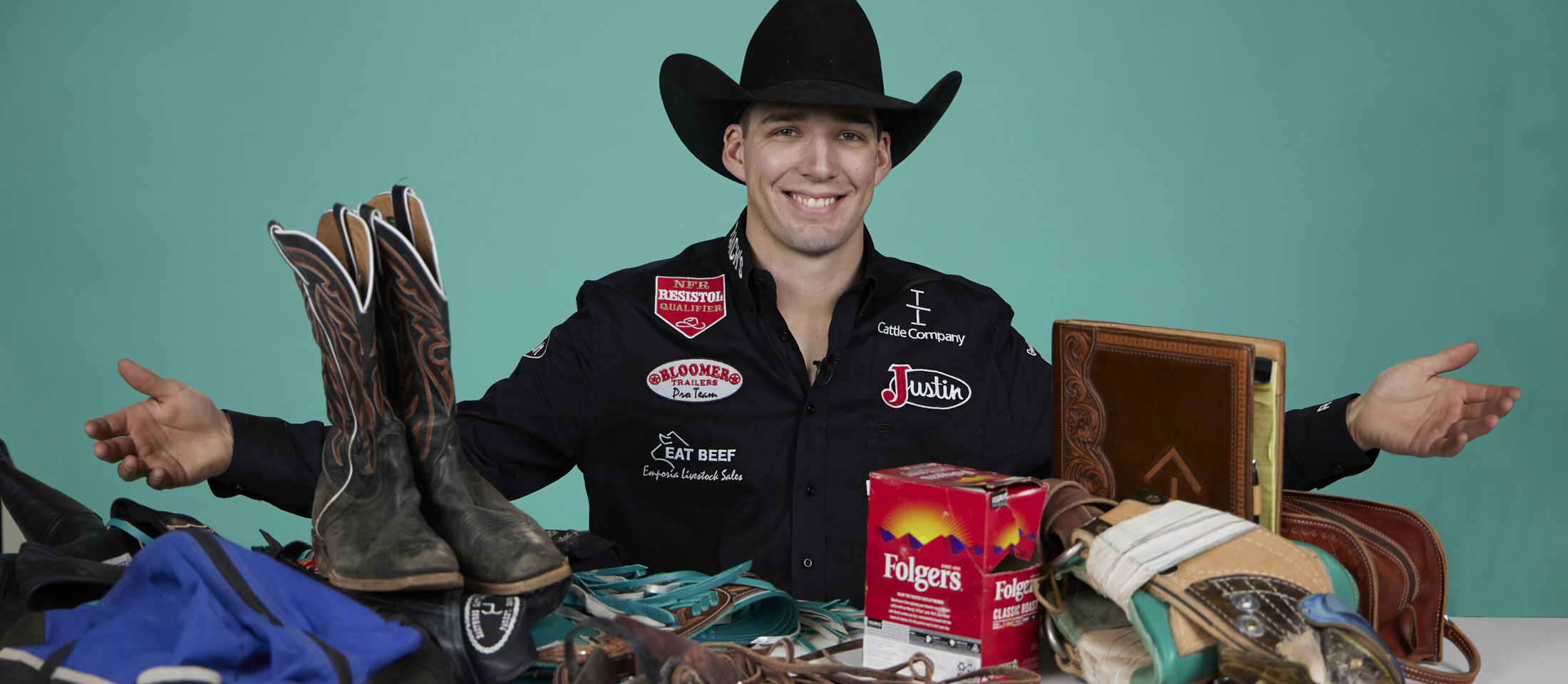 Jess Pope posing with arms open behind his boots, coffee, and other things on a desk.